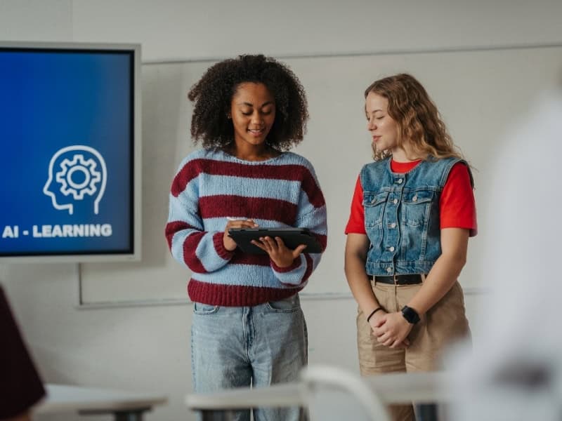 Two students reviewing content on a tablet during an AI learning lesson in a classroom setting